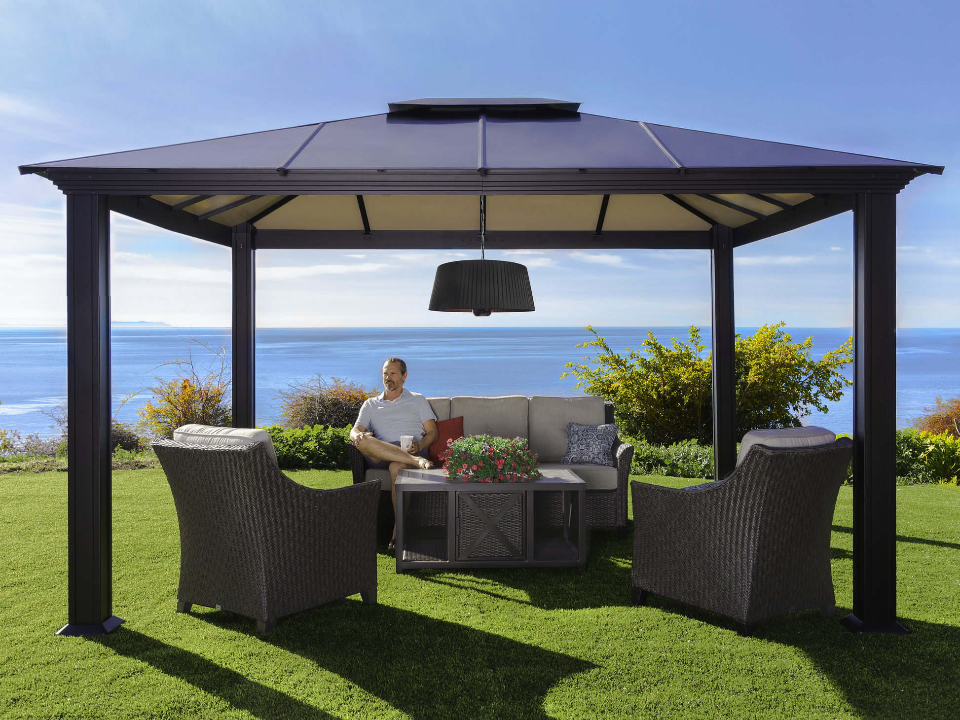 Glow pendent heat lamp hanging from Paragon Outdoor Santa Monica Gazebo with man sitting underneath