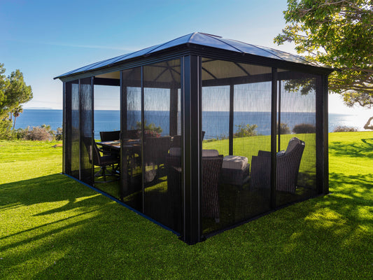 Side angle of the Siena Hard Top Gazebo with mosquito net sides in backyard overlooking the ocean.